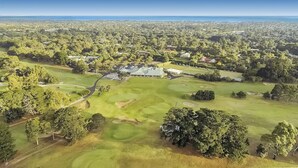 An aerial view of a golf course with a clubhouse, surrounded by dense greenery and residential areas. - Fairways Resort (Rosebud)