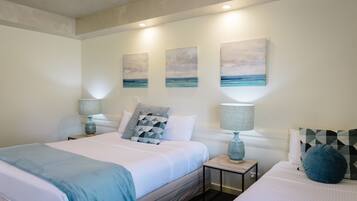 A bedroom with a bed, two bedside tables, and three wall-mounted paintings.