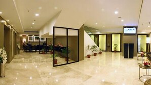 Un vestíbulo de hotel con mostrador de recepción, zona de estar y una escalera.