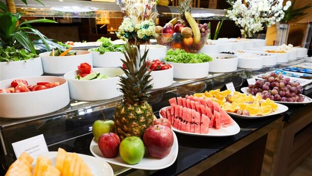 Un bufé con diversas frutas y verduras, entre ellas manzanas, sandía y naranjas.