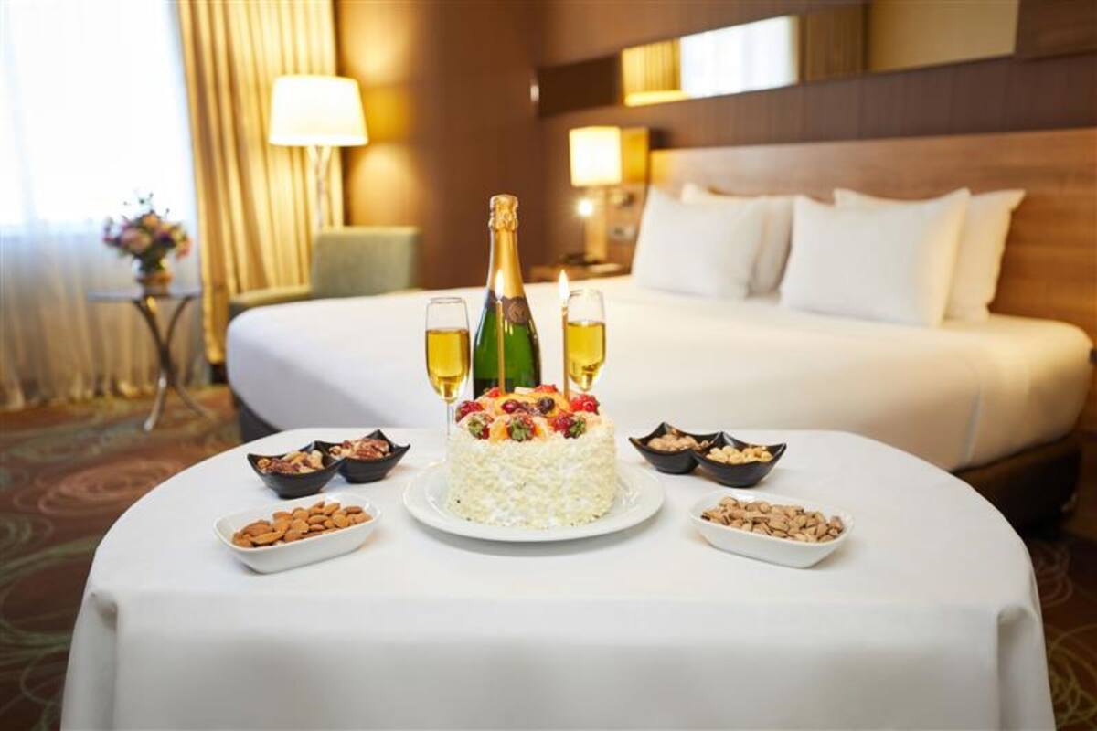 A neatly arranged breakfast table with a cake, champagne, and nuts in a hotel room.