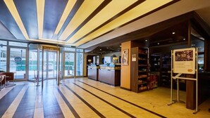 Un vestíbulo de hotel con mostrador de recepción, escritorio de información y zona de estar.