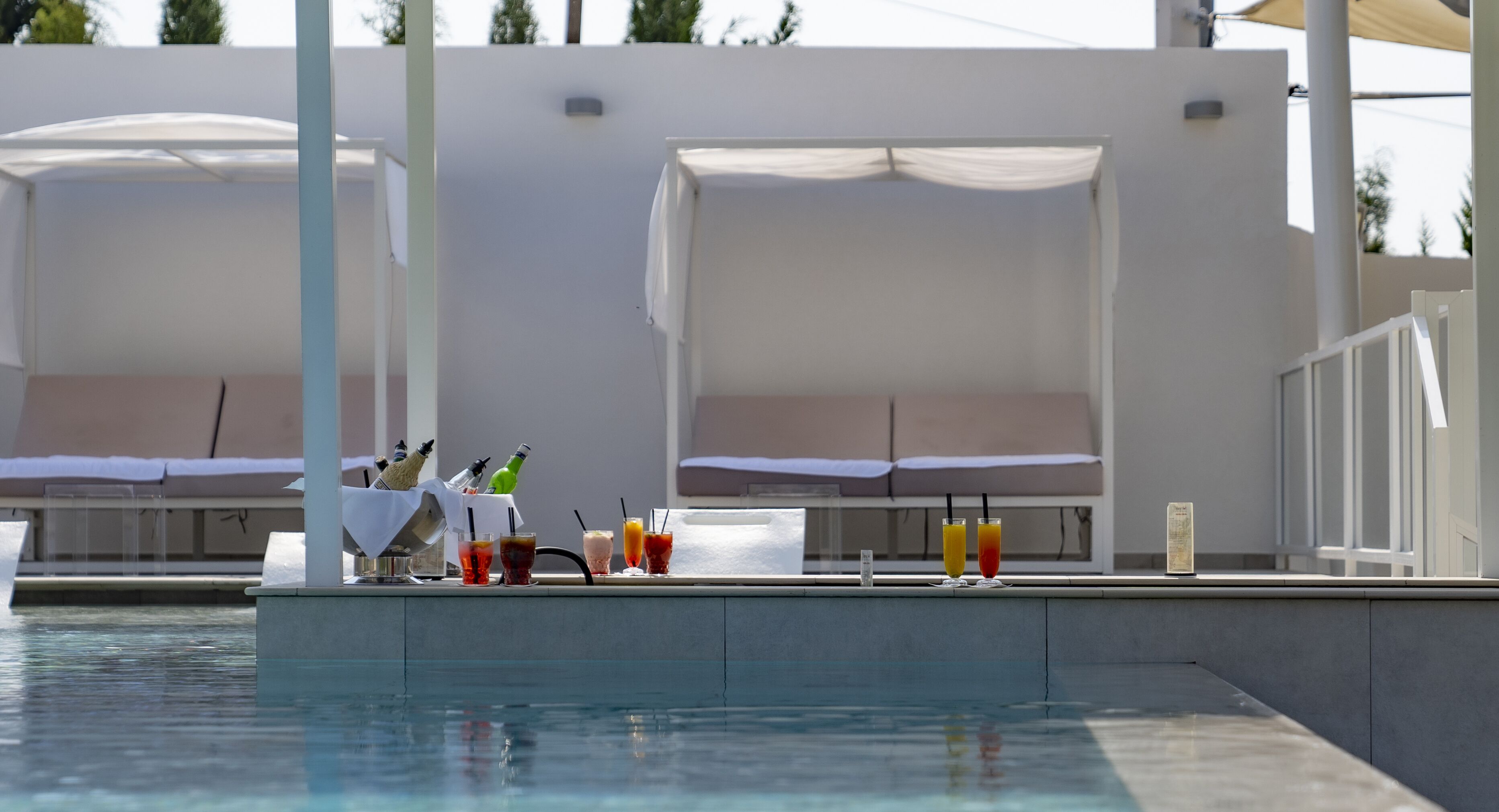 A poolside area with lounge chairs, a bar with drinks, and a pool.