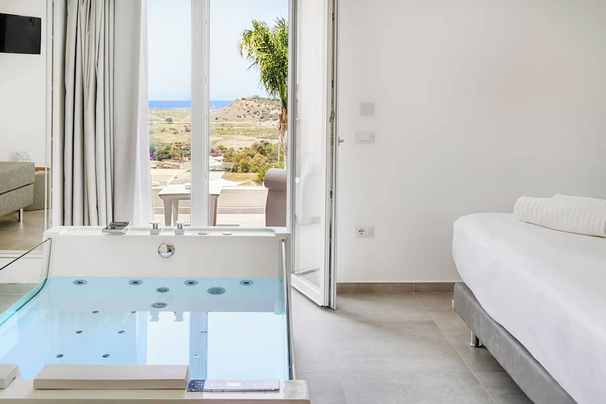 Una habitación de hotel moderna con una bañera, una cama y vistas al campo.