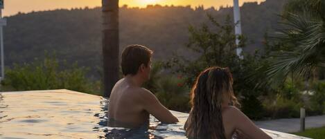 A couple in a hot tub with a sunset view.
