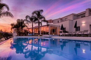 Relax by the pool surrounded by lush palm trees and the hotel's sleek architecture.