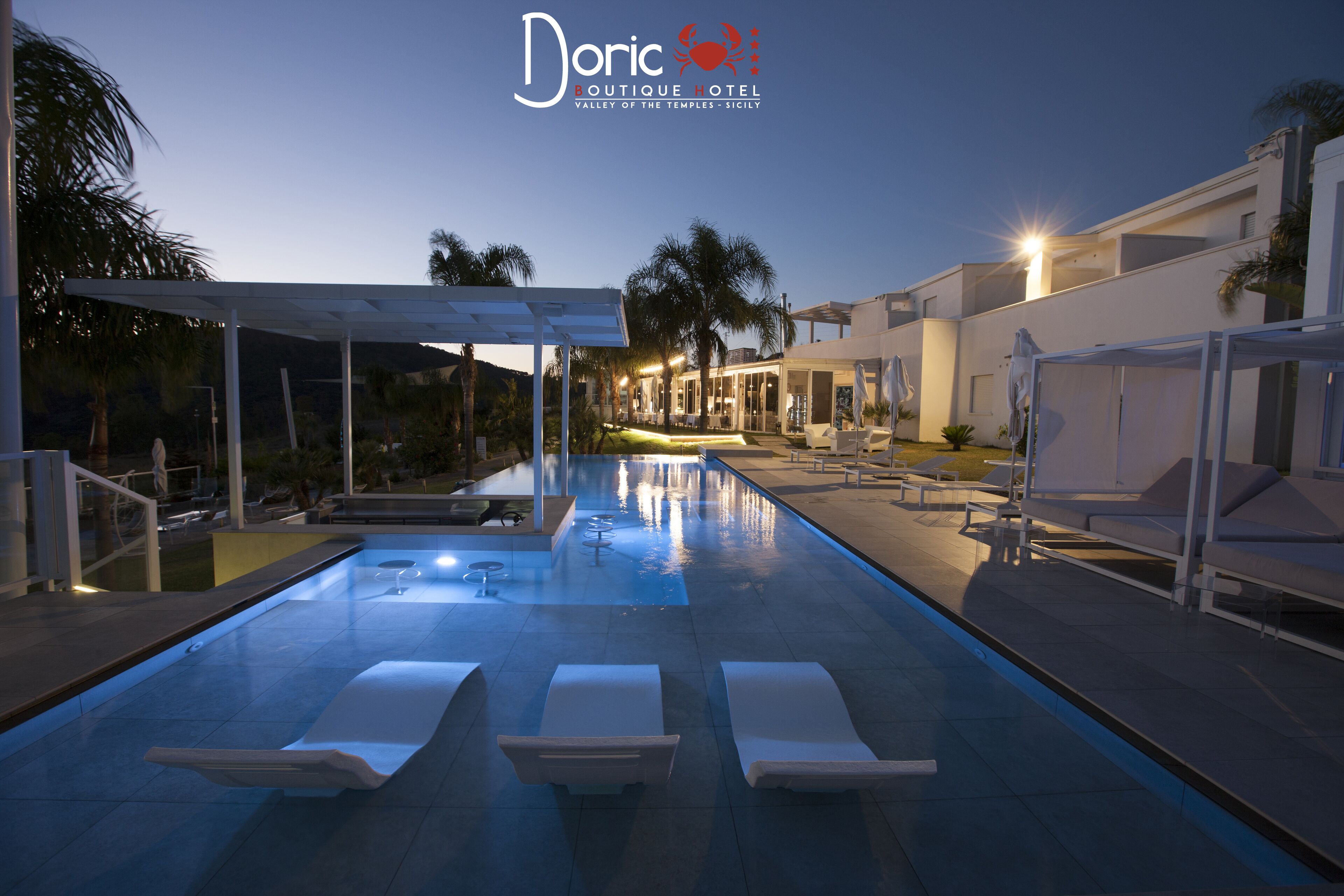 An outdoor swimming pool with lounge chairs and a covered seating area at the Doric Boutique Hotel in the Valley of the Temples, Sicily.