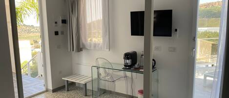 A hotel room with a bed, a desk with a chair, a coffee maker, and a TV on the wall.