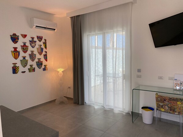 Una sala de estar moderna con un televisor de pantalla plana, una mesa de vidrio y una pared decorativa con cerámica.