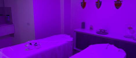 A room with two beds, a vanity with a mirror, and wall-mounted decorative vases.