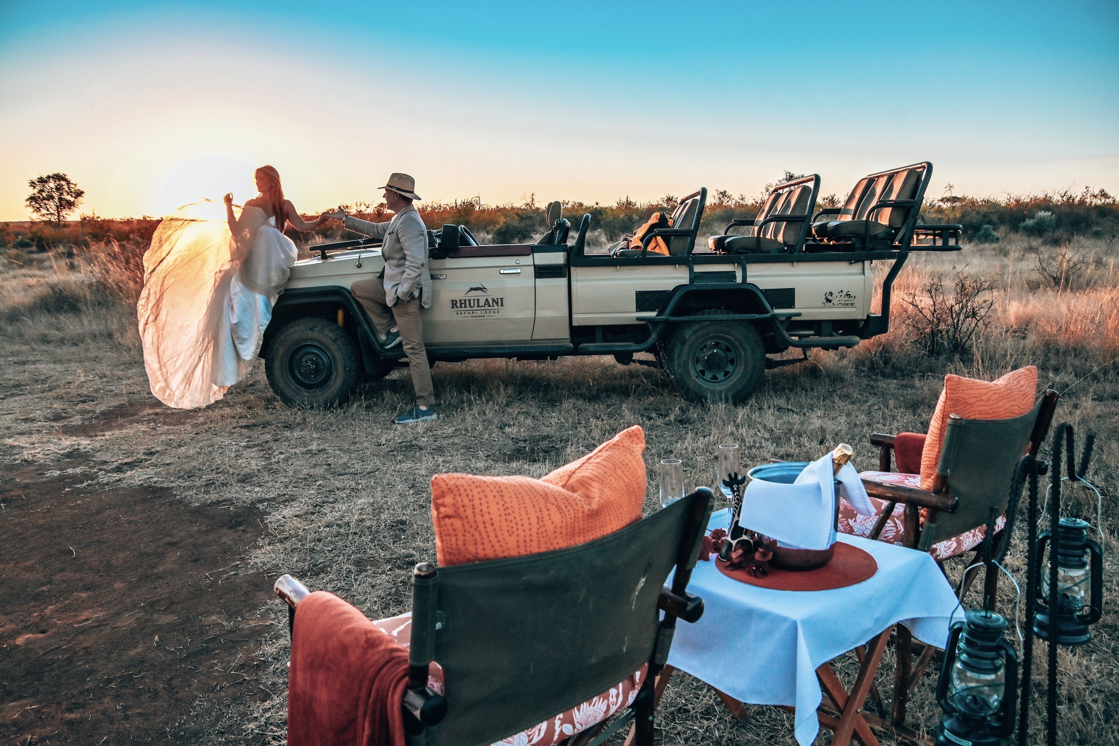 A safari vehicle with a table and chairs set up for an outdoor meal.