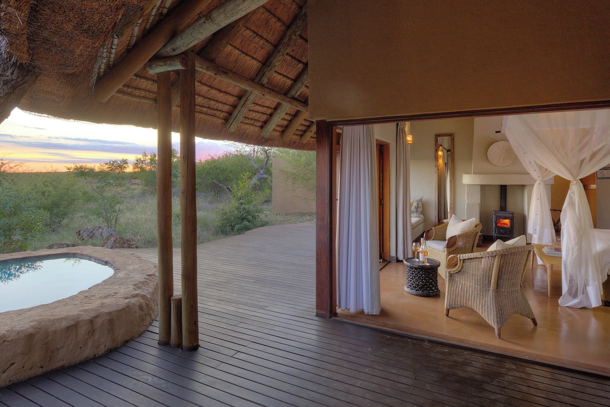 A wooden deck with a hot tub, a bedroom with a canopy bed, and a view of the landscape.