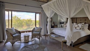 Un dormitorio con cama con dosel, mobiliario de mimbre y vistas al exterior.