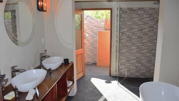A bathroom with two sinks, a large mirror, a bathtub, and a shower area.