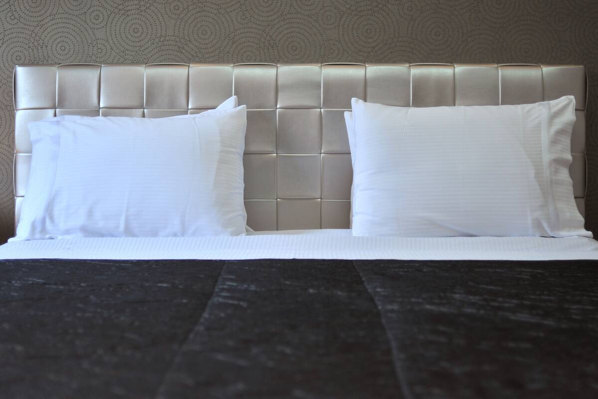 A neatly made bed with a tufted headboard and two pillows.