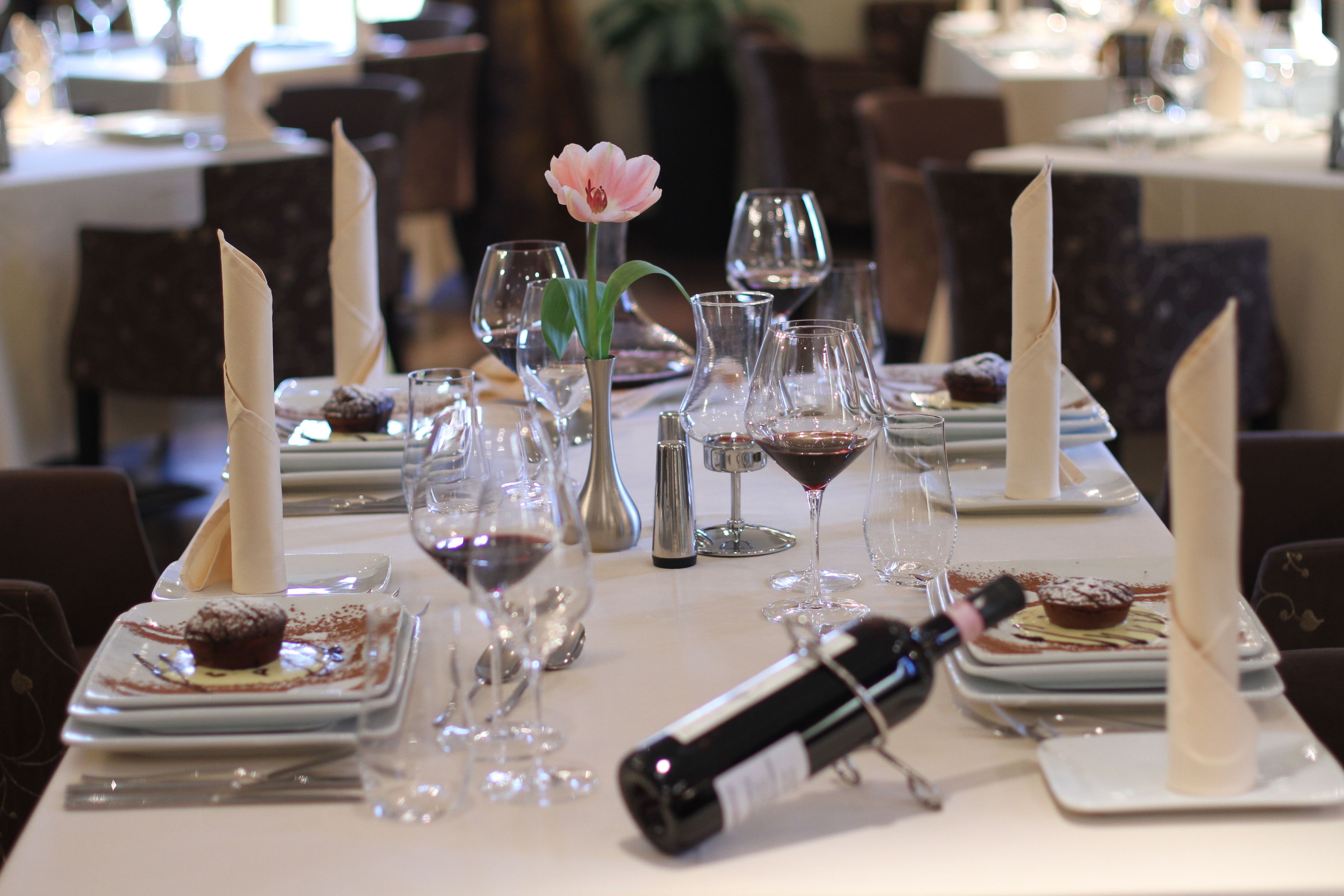 A dining table set with plates, wine glasses, and a candle.
