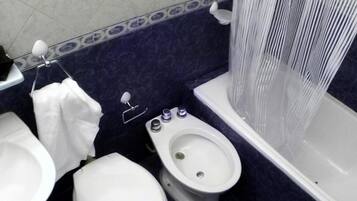 A bathroom with a toilet, bidet, and bathtub.