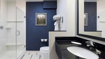 Un baño moderno con cabina de ducha de vidrio, un lavabo blanco y un espejo grande.