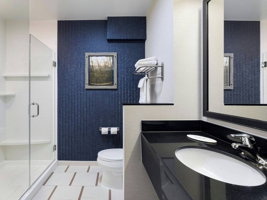Un baño moderno con cabina de ducha de vidrio, un lavabo blanco y un espejo grande.