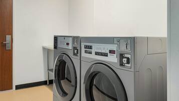 A laundry room with two front-loading washing machines and a small table.