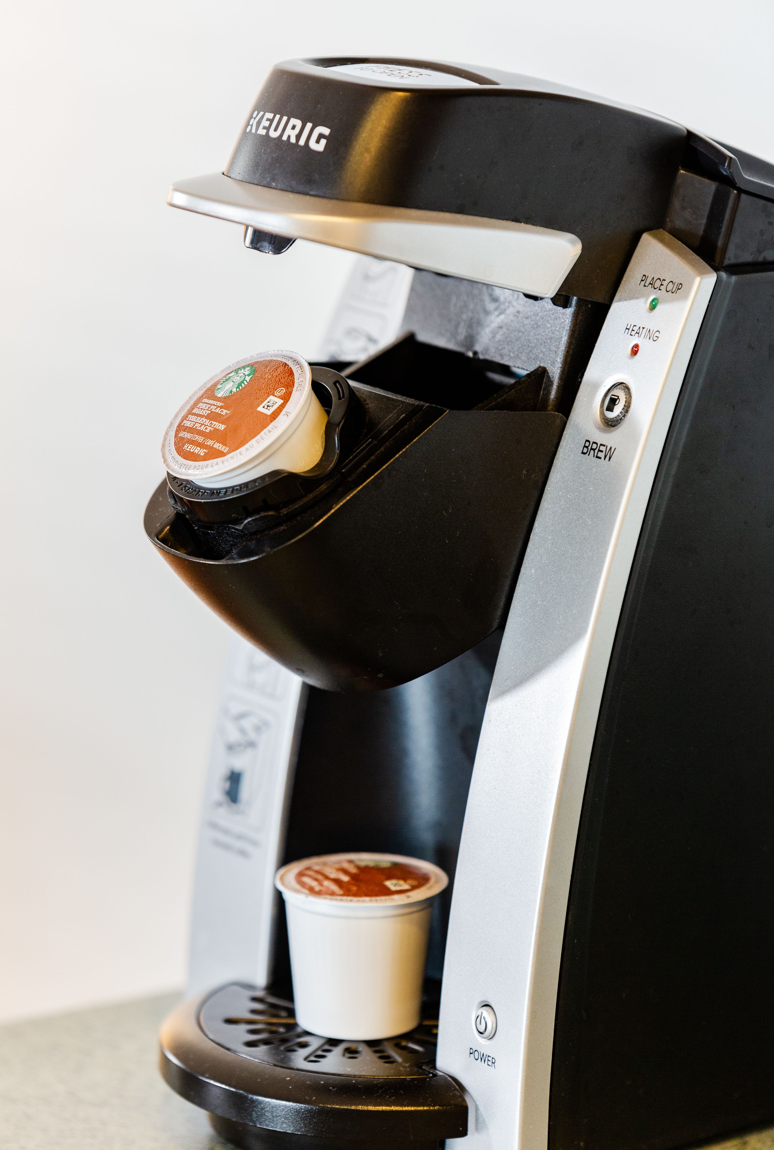 Eine Kaffeemaschine von Keurig mit einer Kaffeekapsel, einer Kaffeetasse und einem Ein-Knopf.