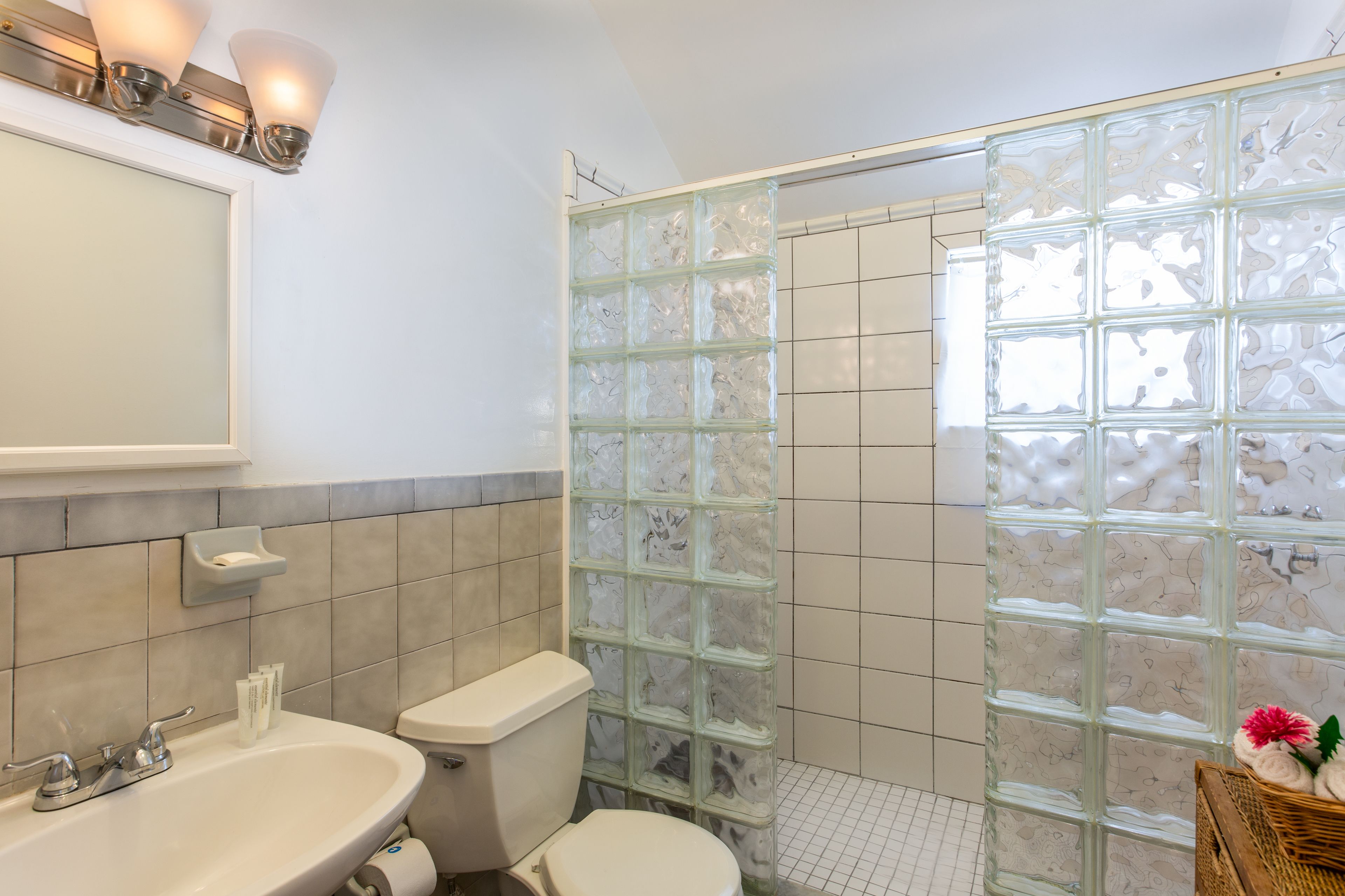A bathroom with a glass shower enclosure, a sink with a soap dish, and a toilet.