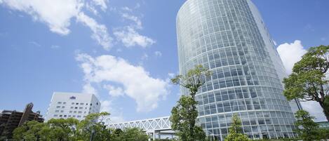 A modern glass building with a curved facade, surrounded by a well-maintained grassy area and trees.