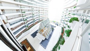 A multi-level atrium with a central open space, surrounded by balconies with greenery. - Hotel Kyocera (Kirishima)
