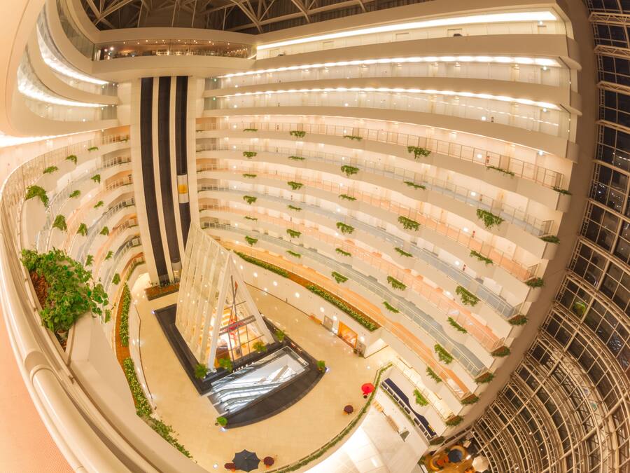 Un atrio de varios niveles con un espacio central abierto, varios balcones y vegetación.