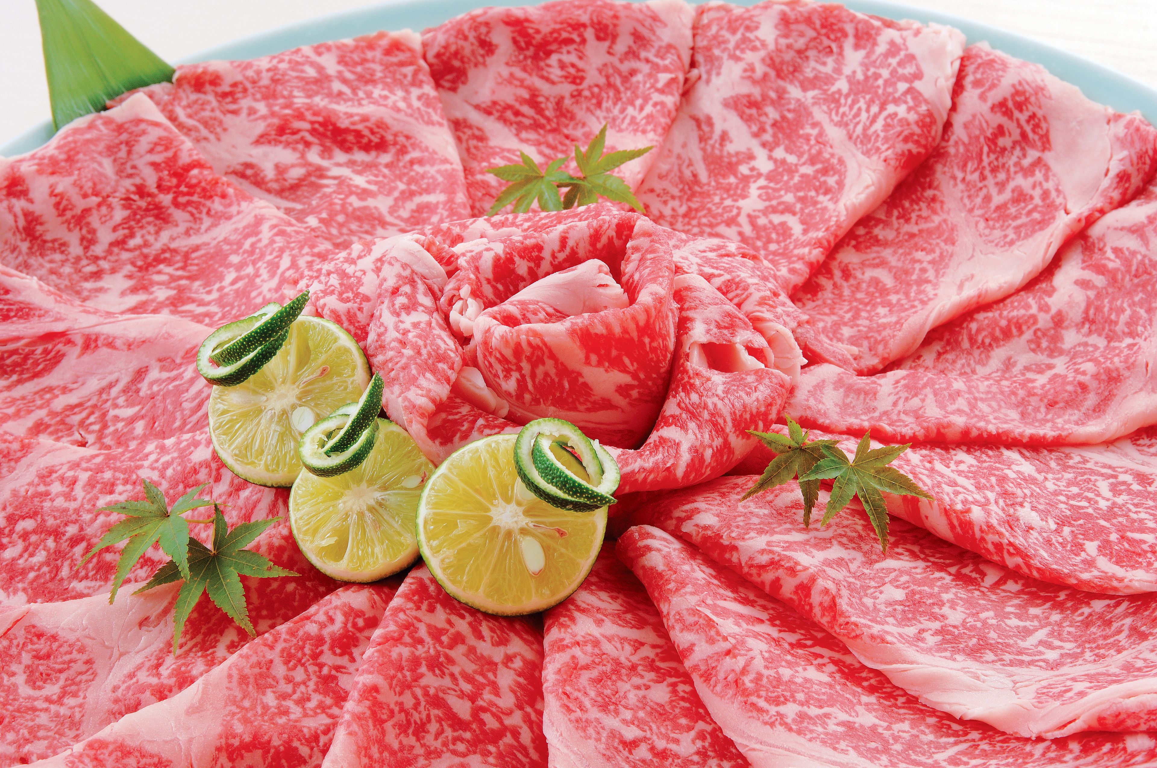 Un plato de carne en rodajas con lima y hojas verdes.