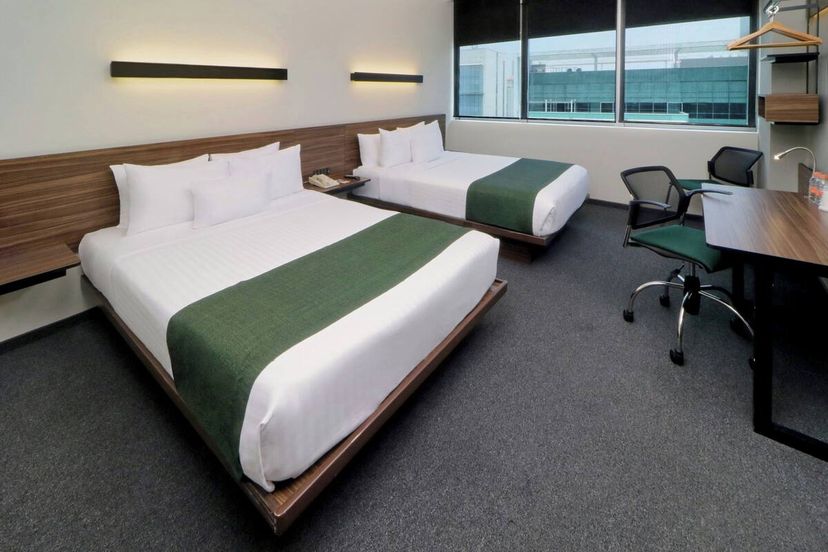 A hotel room with two beds, a desk, and a chair.