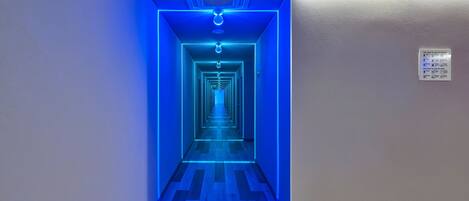 Un couloir éclairé de lumière bleue et un panneau fixé au mur.