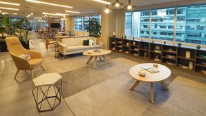 A modern hotel lobby with a sofa, armchairs, a coffee table, and a bookshelf. - City Express Plus by Marriott Ciudad de México Santa Fe (Mexico City)