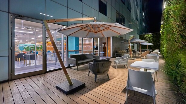 An outdoor seating area with wooden flooring, modern chairs, and umbrellas. - City Express Plus by Marriott Ciudad de México Santa Fe (Mexico City)
