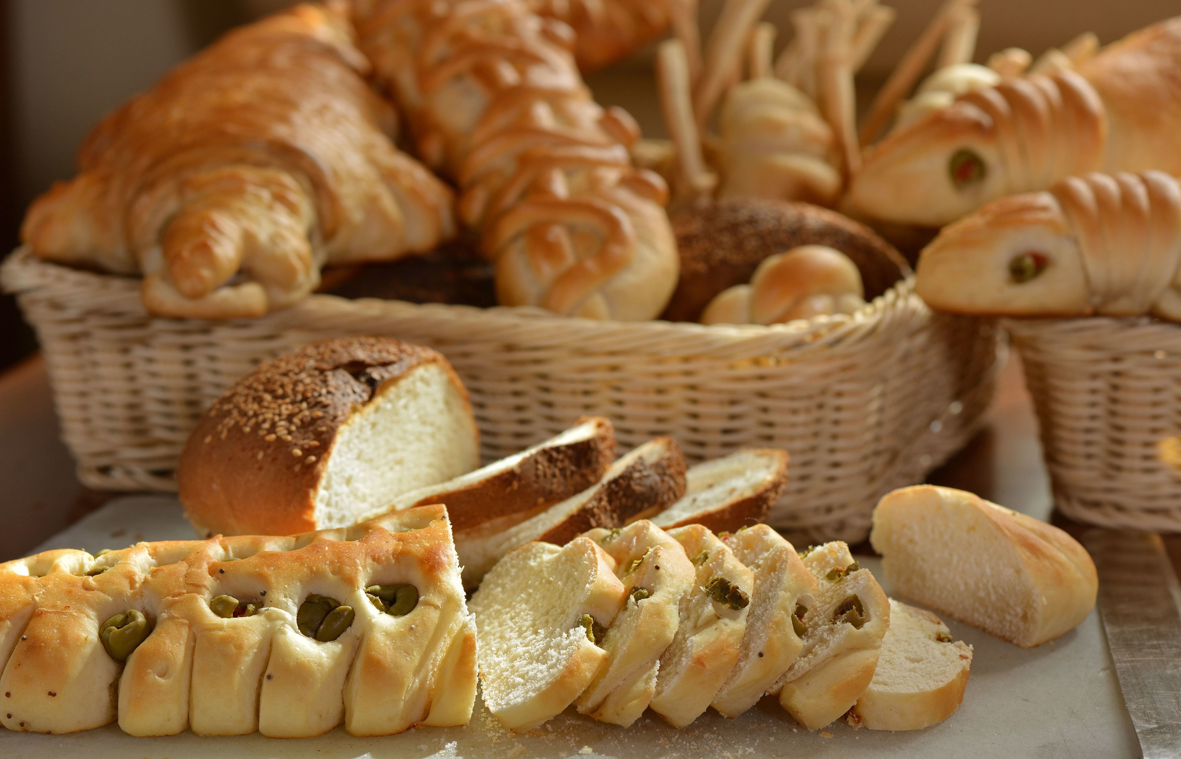 Variedad de panes y pasteles, incluyendo croissants y panecillos, exhibidos en cestas de mimbre.