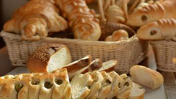 Variedad de panes y pasteles, incluyendo croissants y panecillos, exhibidos en cestas de mimbre.
