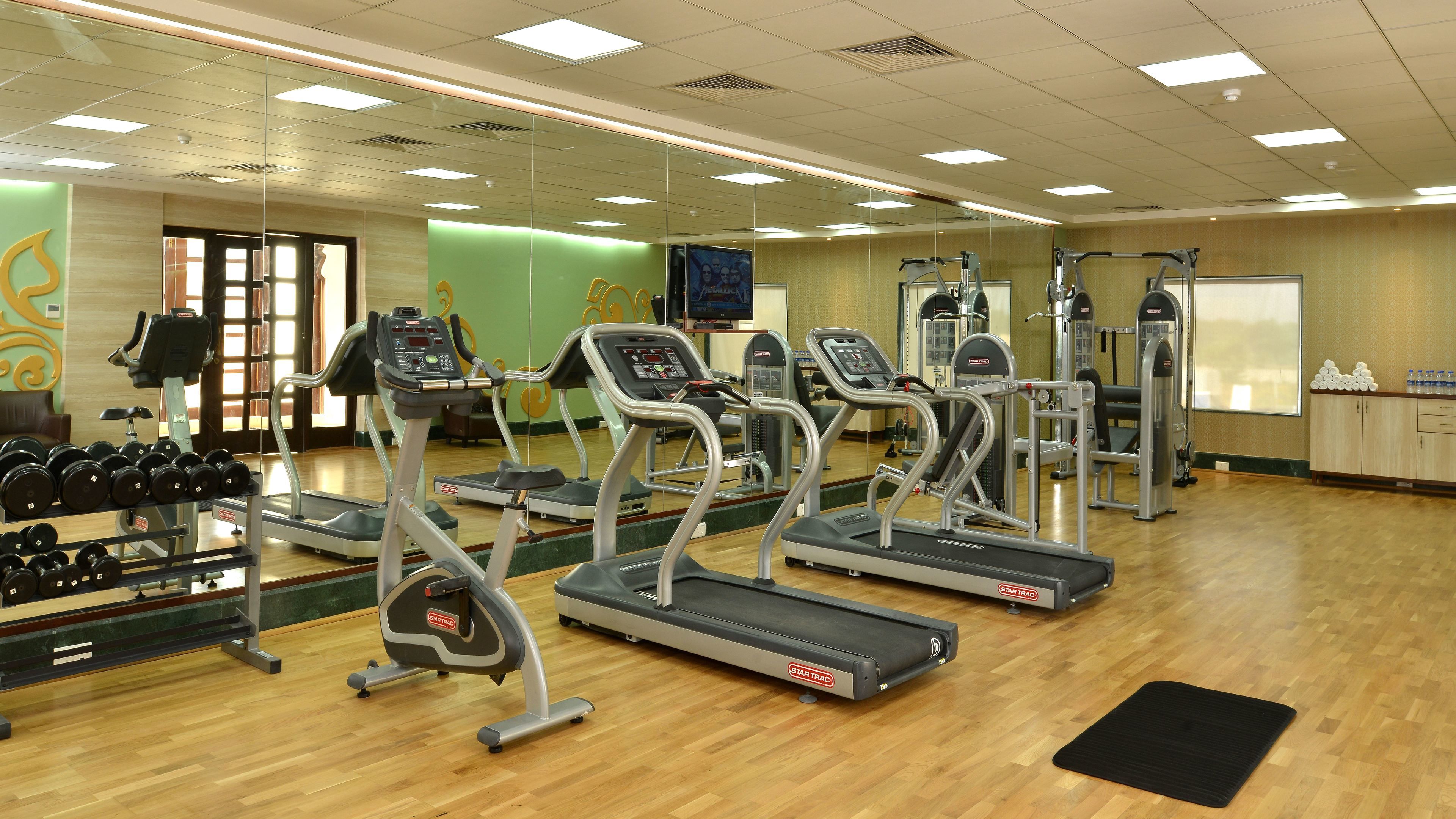 Un gimnasio con cintas de correr, mancuernas y máquinas de pesas.