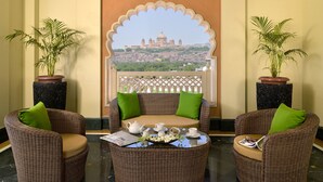 A seating area with wicker furniture, green cushions, and a table with tea set.