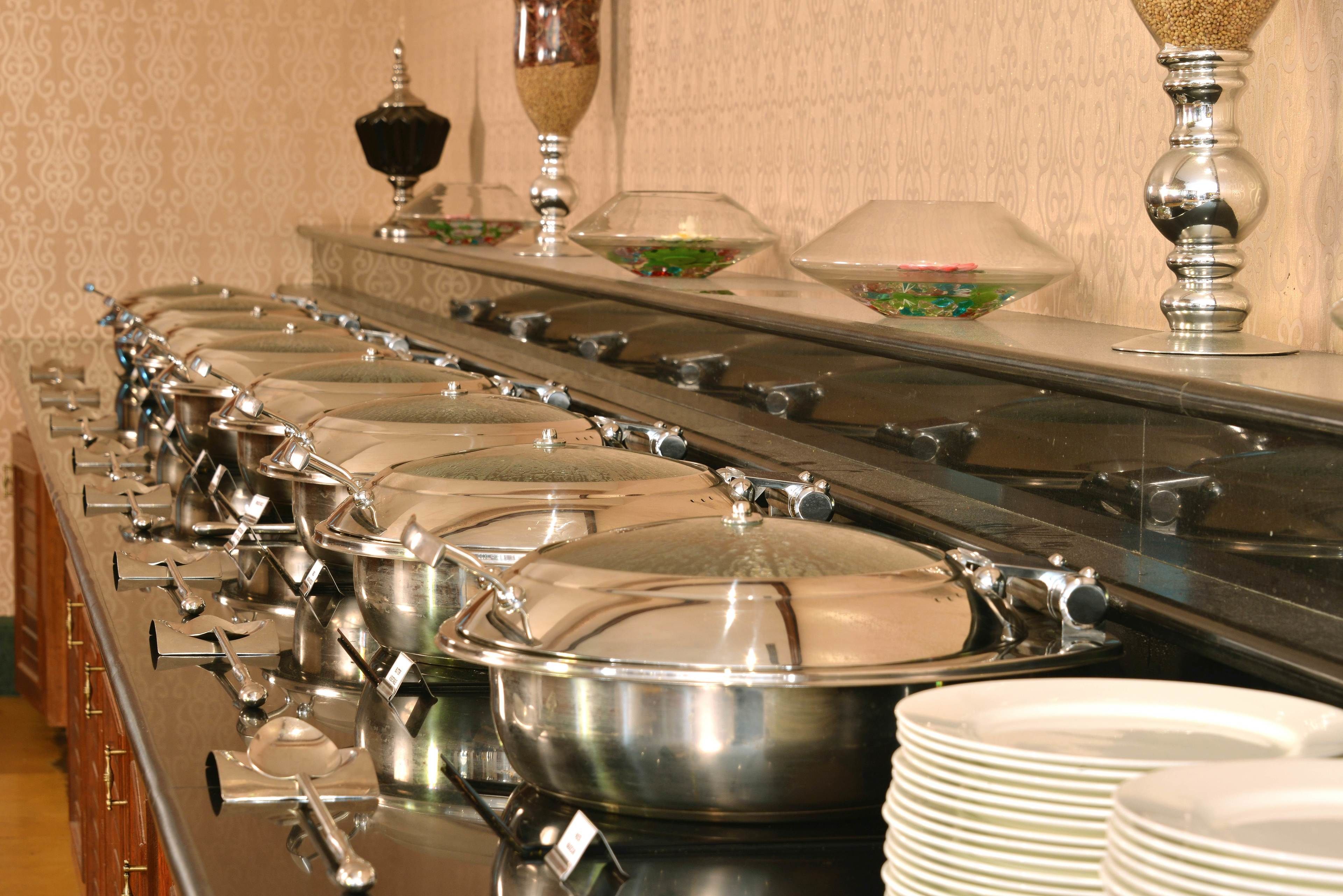 Tarjolla on runsas buffet, jossa on useita eri pisteitä, ja jokaisessa pisteessä on suuri kattila ja kauha.