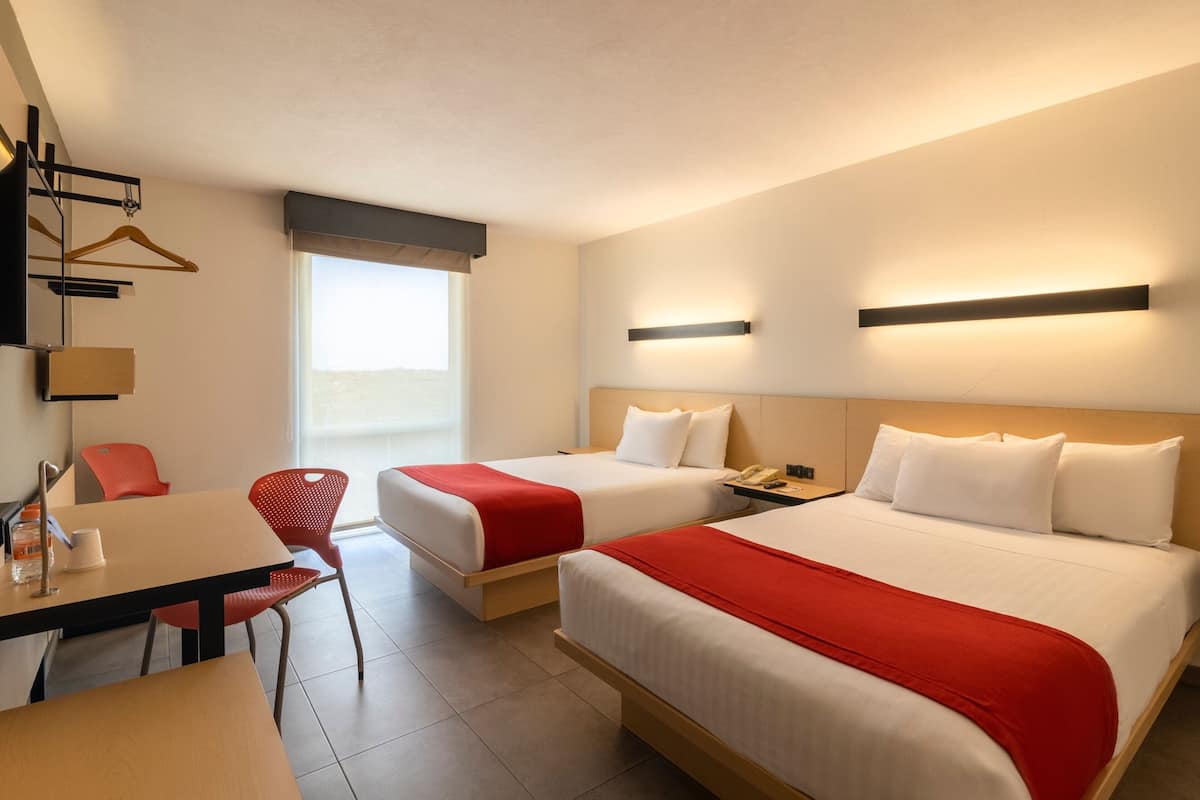 Habitación de hotel con dos camas, un escritorio y una silla.