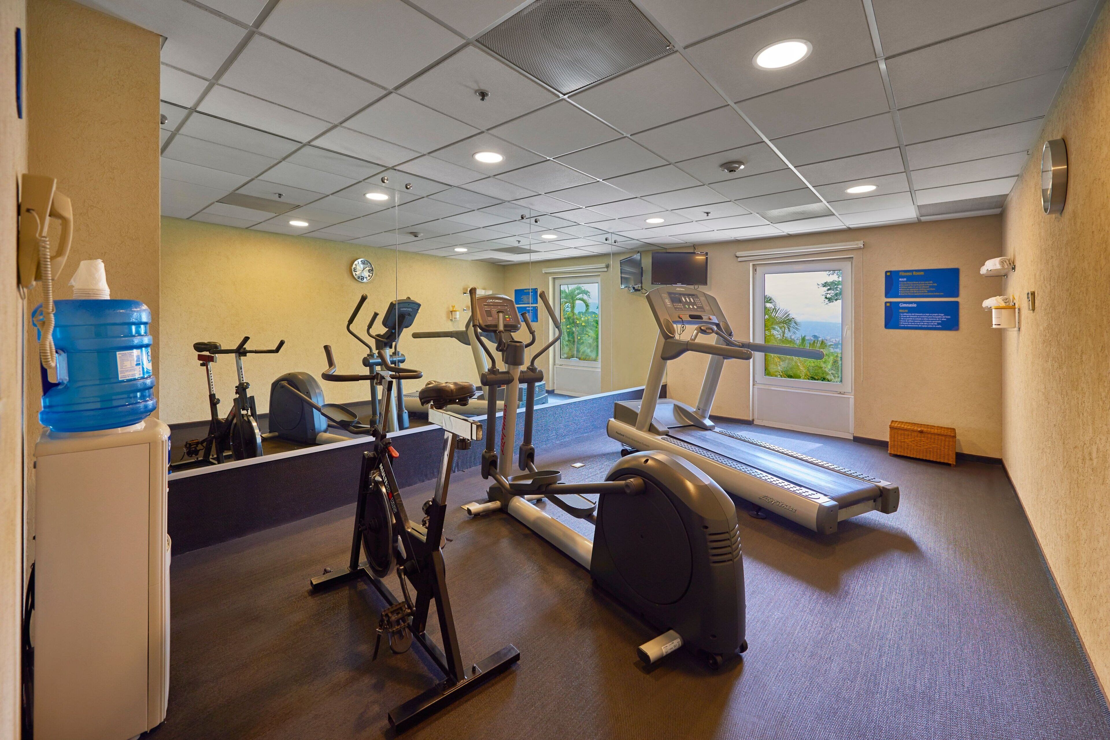 Un centre de remise en forme équipé de machines de cardio, d’un distributeur d’eau et de matériel d’exercice.