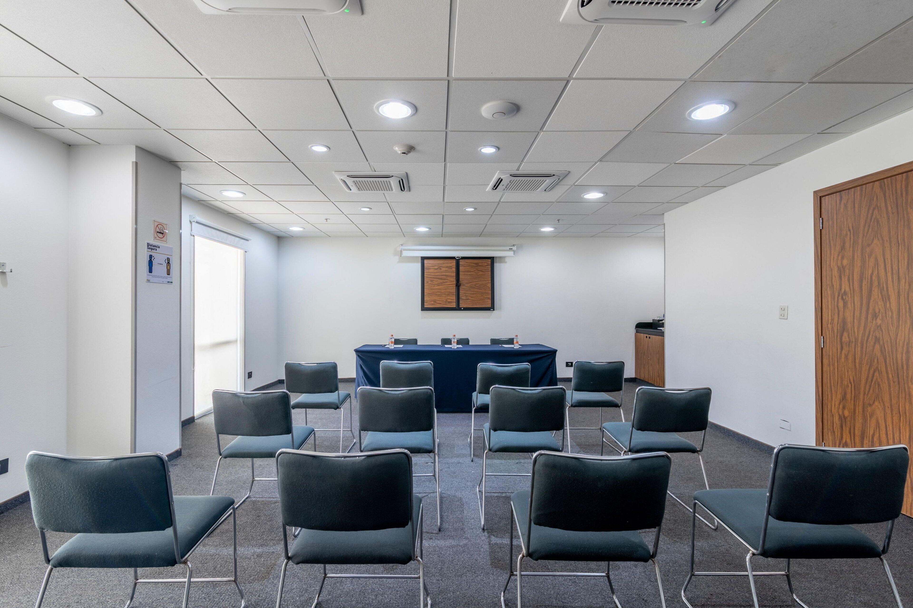 A conference room with a long table, multiple chairs, and a wooden door.