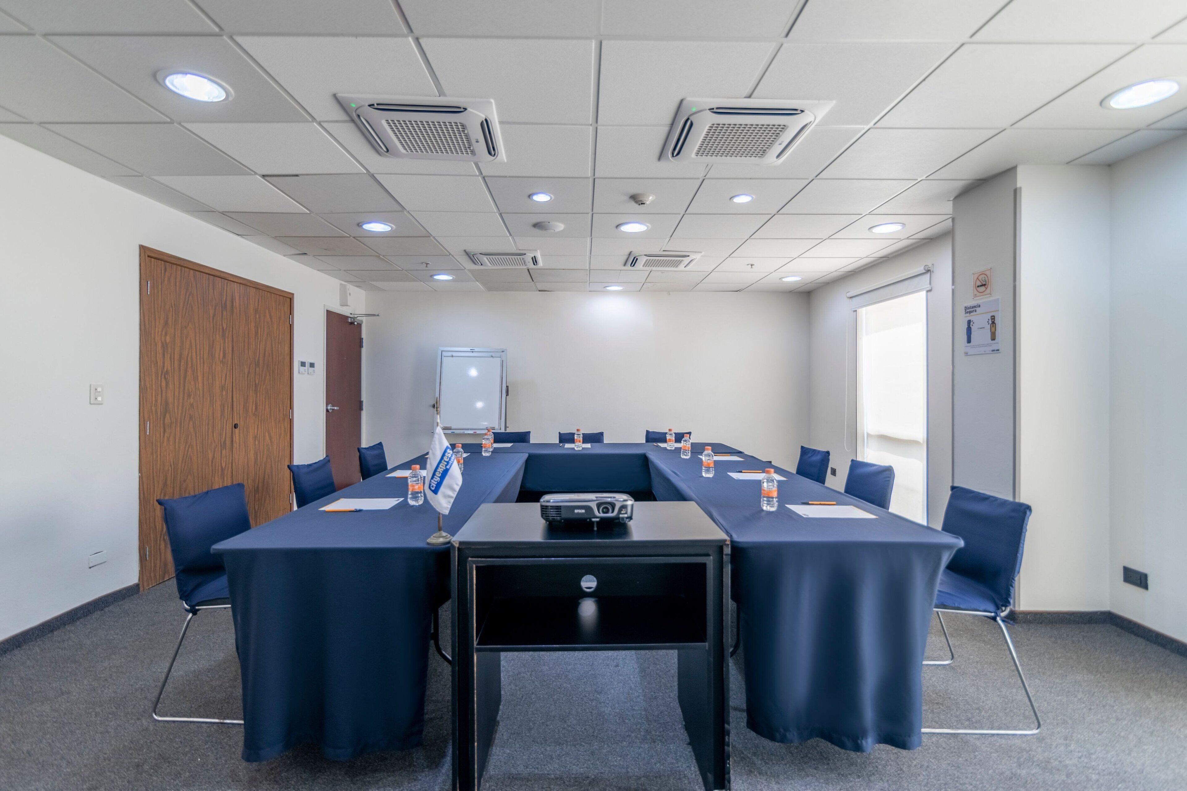 A conference room with a long table, chairs, a projector, and water bottles.