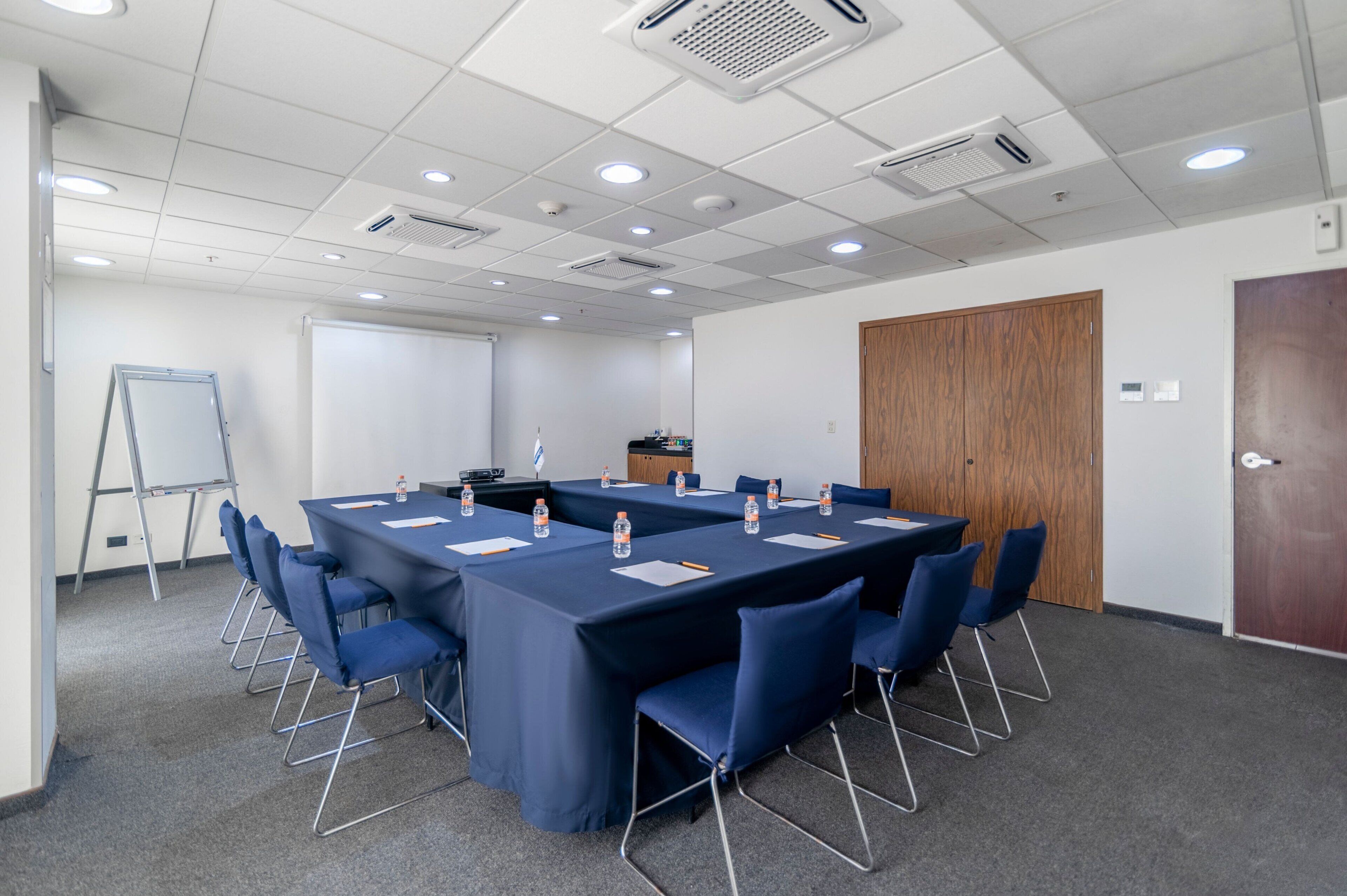 A conference room with a long table, blue chairs, and a whiteboard.