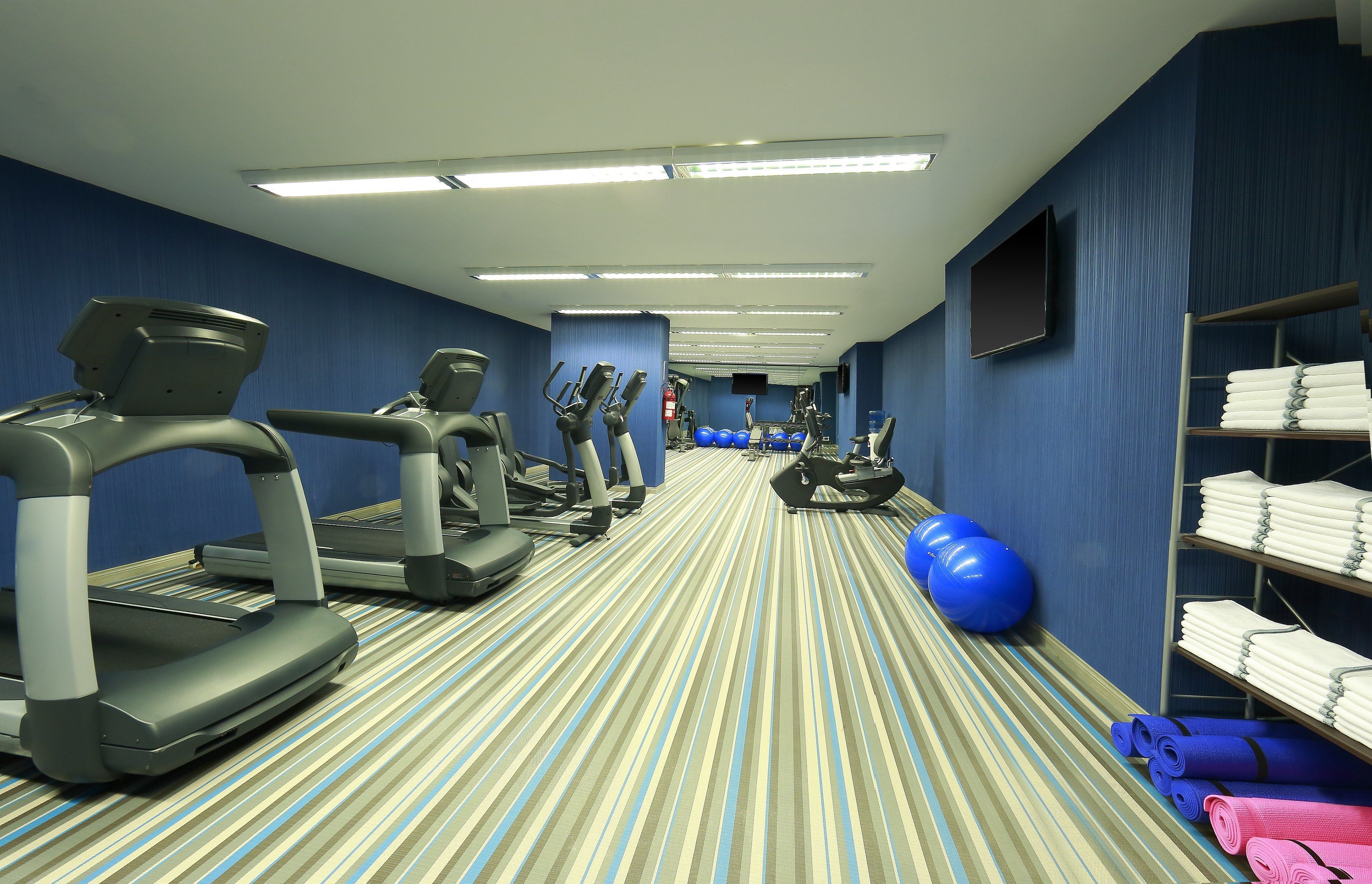 A hotel gym with treadmills, elliptical machines, and exercise balls.