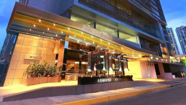 Een modern hotel met een opvallende ingang, meerdere verdiepingen en een goed verlichte gevel.