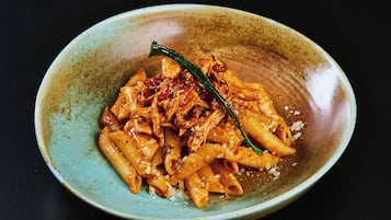 Un plato de pasta con un chile verde como adorno, sobre un plato de cerámica con motas.