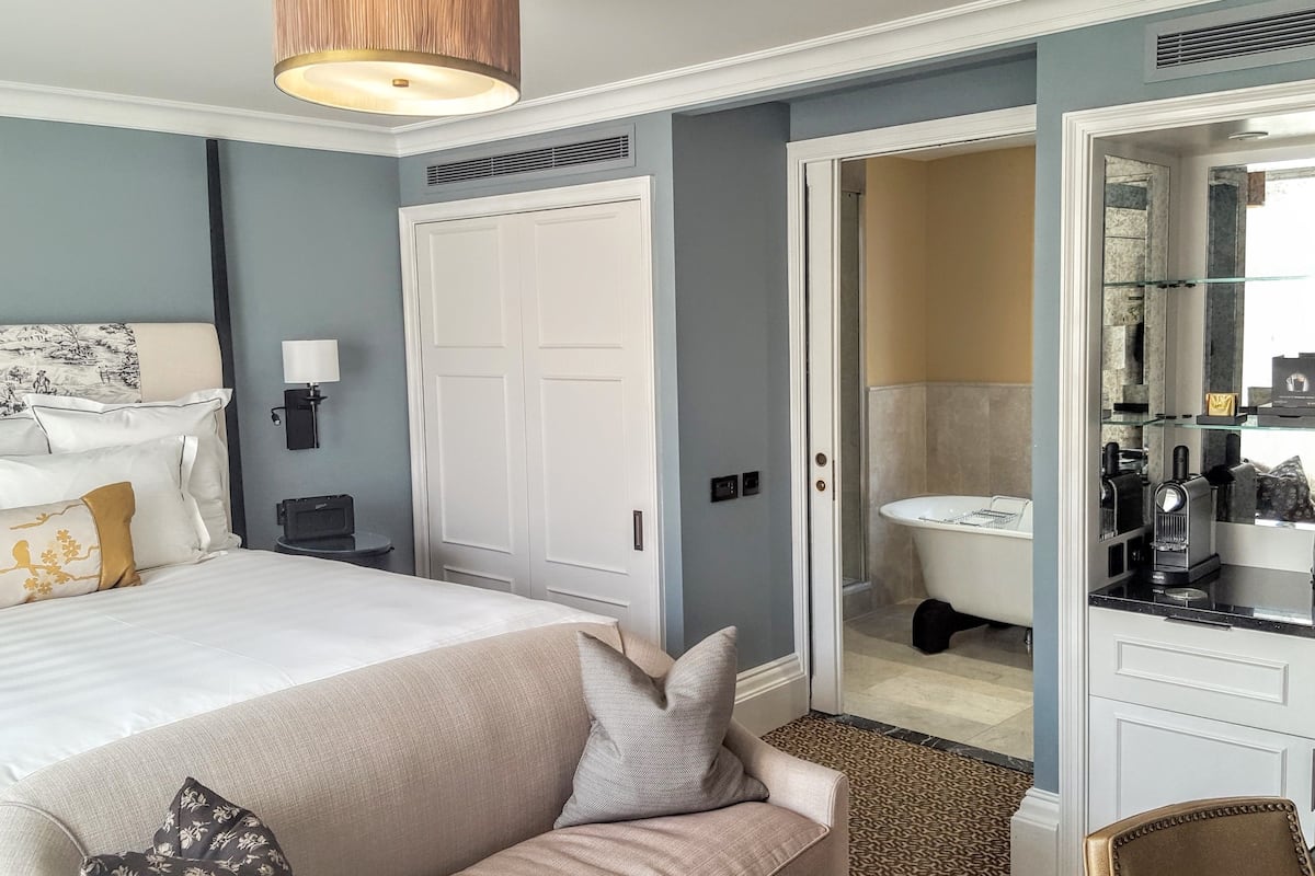 Ein Hotelzimmer mit Bett, einer Couch, einem Badezimmer mit Badewanne und einem Spiegel.