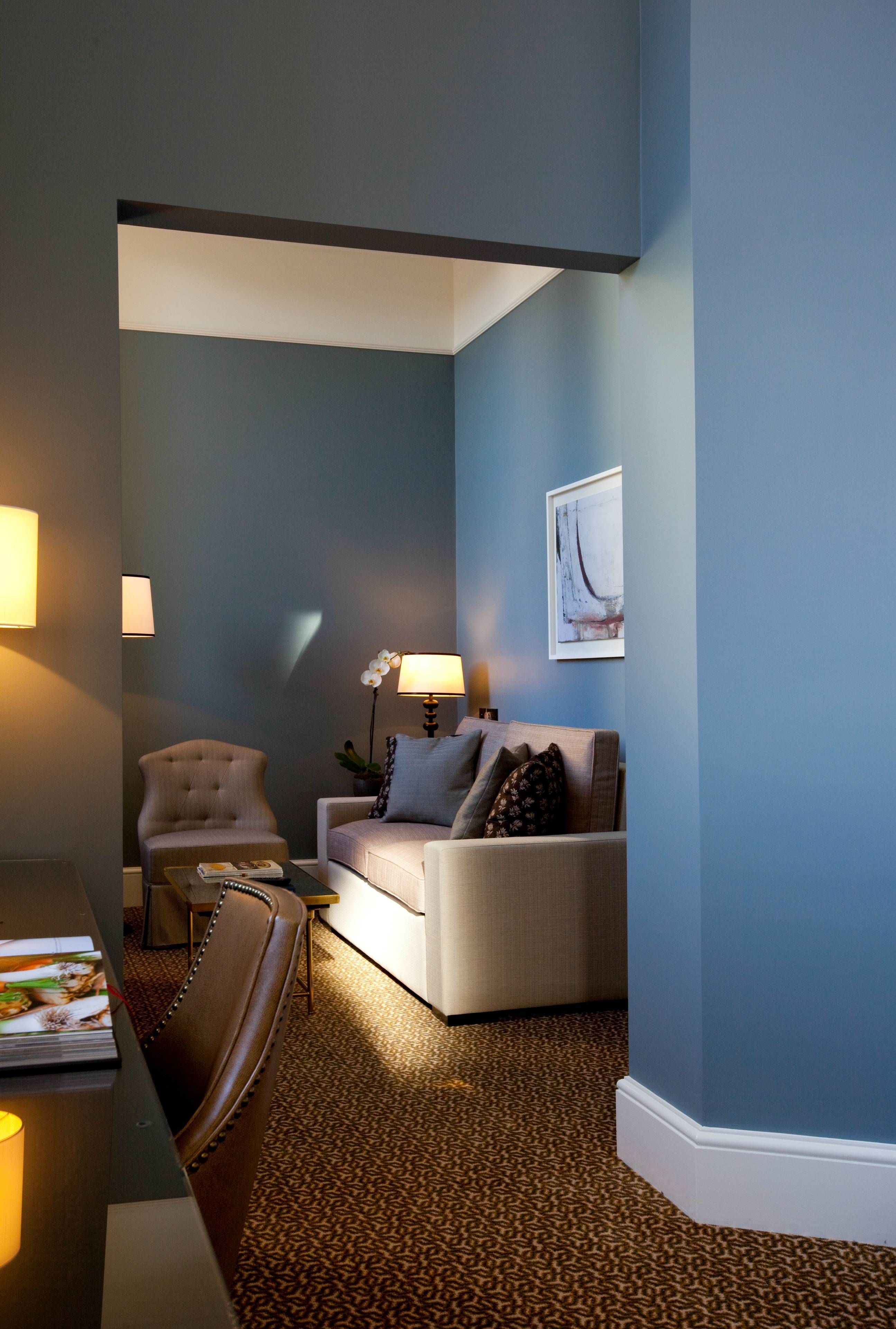 Una sala de estar moderna con una pared azul de acento, un sofá blanco, un sillón color beige y una mesa de centro.