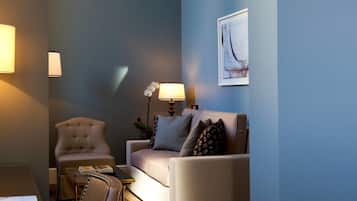 Una sala de estar moderna con una pared azul de acento, un sofá blanco, un sillón color beige y una mesa de centro.
